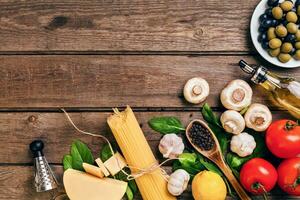 Pasta ingredients - tomatoes, olive oil, garlic, italian herbs, fresh basil, salt and spaghetti on a wooden background with copy space, horizontal, top view photo