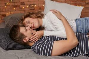 Caucasian young beautiful couple lie on bed and hugging each other photo