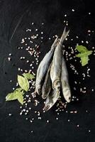 Bunch of dried mullet with condiments on black background photo