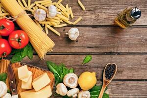 Ingredients for spaghetti with basil, tomatoes, cheese on wooden background, top view, place for text photo