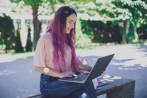 Young girl is studying in the spring park, sitting on the wooden photo