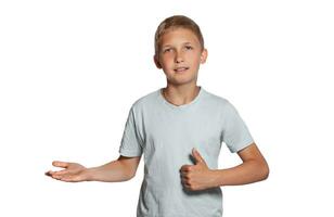 Close-up portrait of a blonde teenage boy in a white t-shirt posing isolated on white studio background. Concept of sincere emotions. photo