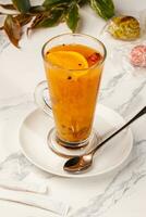 Glass cup of vitamin fragrant tea from sea buckthorn and orange with cinnamon stick photo