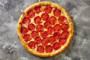 Spicy pepperoni pizza with tomato sauce and mozzarella on gray stone background photo