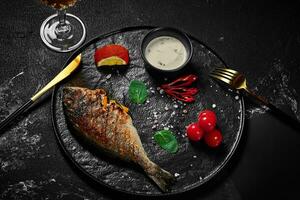 Grilled dorado stuffed with orange with yogurt sauce, chili peppers, cherry tomatoes photo