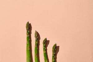 Uncooked green asparagus spears on pink background. Concept of healthy nutrition, food and seasonal vegetables harvest. Close up, copy space photo