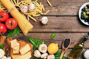 Ingredients for spaghetti with basil, tomatoes, cheese on wooden background, top view, place for text photo