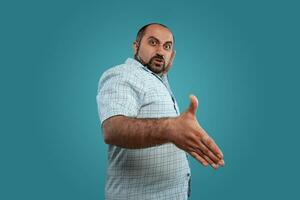 Close-up portrait of a brunet middle-aged man with beard, dressed in a light checkered shirt and posing against a blue background. photo