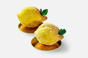 Two lemon shaped shortcrust pastry cakes covered in sugar with citrus curd filling photo