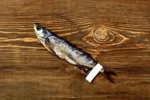 Jerked salted Baltic herring with paper label on tail on wooden table photo