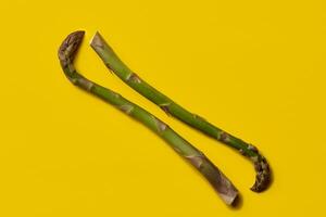 Two ripe green asparagus stems against yellow background. Healthy nutrition, food and seasonal vegetables harvest. Close up, copy space photo