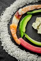 Slices of salmon, tuna, eel, shrimps, avocado, rice and Japanese mayonnaise on black photo