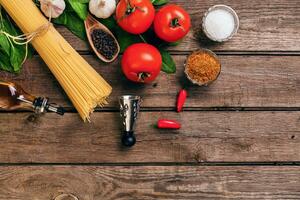 Pasta and ingredients on wooden background with copy space. Top view. Vegetarian food, healthy or cooking concept. photo