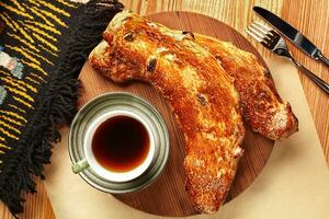 Traditional freshly baked sweet Georgian bread nazuki with raisins served with cup of tea on wooden serving board. Authentic national bakery concept photo