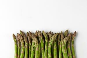 Green raw asparagus spears isolated on white studio background. Healthy nutrition, food and seasonal vegetables harvest. Close up, flat lay, top view photo