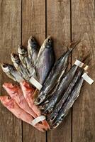 Dried salted roach, sabrefish and red mullets with labels on tails on wooden background photo