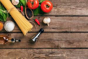 Pasta and ingredients on wooden background with copy space. Top view. Vegetarian food, healthy or cooking concept. photo