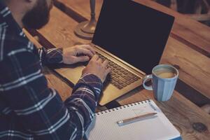 Cropped image of young man chatting via net-book during work bre photo