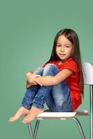 little girl wearing red t-short and posing on chair photo