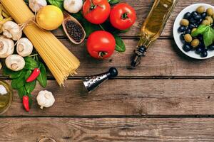 Pasta and ingredients on wooden background with copy space. Top view. Vegetarian food, healthy or cooking concept. photo