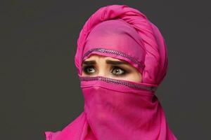 Close-up shot of a young charming woman wearing the pink hijab decorated with sequins. Arabic style. photo