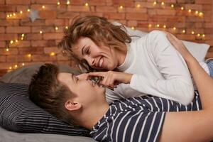 Caucasian young beautiful couple lie on bed and hugging each other photo