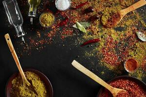 Assorted spices on dark black background. Seasonings for food. Curry, paprika, pepper, cardamom, turmeric. Top view. photo