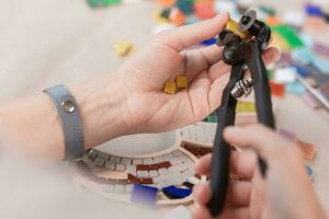 Hands of master working on new modern colorful mosaic. Close-up photo