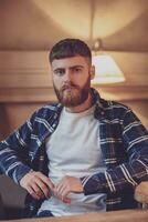 Portrait handsome bearded man wearing plaid shirt at modern cafe photo