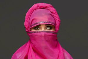 Close-up shot of a young charming woman wearing the pink hijab decorated with sequins. Arabic style. photo