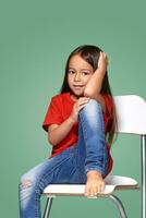 little girl wearing red t-short and posing on chair photo