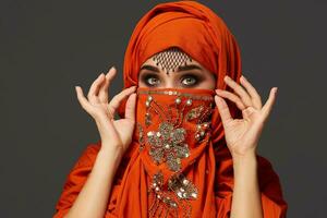 Studio shot of a young charming woman wearing the terracotta hijab decorated with sequins and jewelry. Arabic style. photo