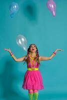 Lovely girl with a multi-colored braids hairstyle and bright make-up, posing in studio with air balloons against a blue background. photo