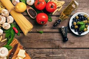 italiano comida tomates para cocinar, albahaca, pasta, aceituna petróleo y queso en de madera fondo, parte superior vista, Copiar espacio. foto