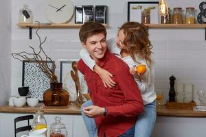 Happy young lovely couple on kitchen hugging each other. They enjoy spending time togehter photo