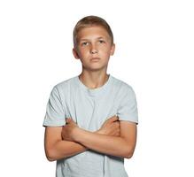 Close-up portrait of a blonde teenage boy in a white t-shirt posing isolated on white studio background. Concept of sincere emotions. photo