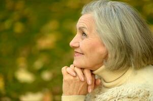 Portrait of senior woman walking in autumn park photo