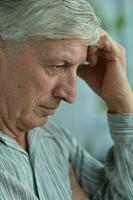 Portrait of an thinking elderly man on a gray background photo