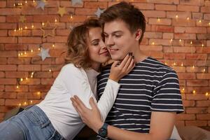 Happy loving couple relaxing on bed at home, young woman touching smiling handsome man face, looking in the eyes. photo