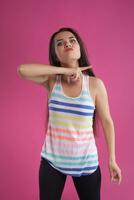 Brunette woman with long hair, dressed in colorful striped shirt, posing against pink studio background. Sincere emotions. Close-up. photo