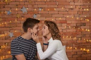 Happy loving couple relaxing on bed at home, young man touching smiling beautiful woman face, looking in the eyes. photo