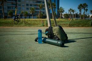 Sports tools on the sports ground. A backpack, bottle of water and rolled fitness mat. Sport. Fitness. Copy advertising space photo