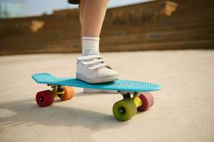 Closeup multicolored skate wheels and foot or leg on back of child or kid girl playing skateboard, or surf skate and start on outdoor pump track in skatepark by extreme sports photo