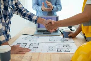 construction engineer joins hands with architect to congratulate housing project that architect team has designed and has been accepted by engineering team. concept of handshake for congratulations photo