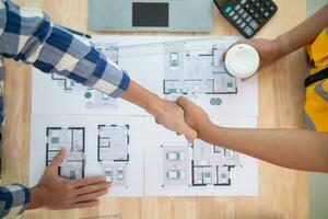 construction engineer joins hands with architect to congratulate housing project that architect team has designed and has been accepted by engineering team. concept of handshake for congratulations photo