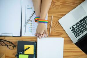 lgbt Q couple wore rainbow wristbands symbolizing lgbt Q group and held hands to show love, friendship and kindness. And lgbt Q couple also promised to love each other forever. Copy space for text photo