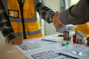 construction engineer joins hands with architect to congratulate housing project that architect team has designed and has been accepted by engineering team. concept of handshake for congratulations photo