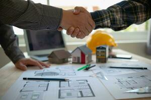 construction engineer joins hands with architect to congratulate housing project that architect team has designed and has been accepted by engineering team. concept of handshake for congratulations photo