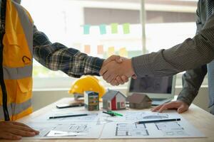 construction engineer joins hands with architect to congratulate housing project that architect team has designed and has been accepted by engineering team. concept of handshake for congratulations photo