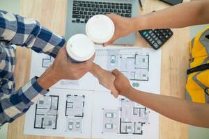 construction engineer joins hands with architect to congratulate housing project that architect team has designed and has been accepted by engineering team. concept of handshake for congratulations photo
